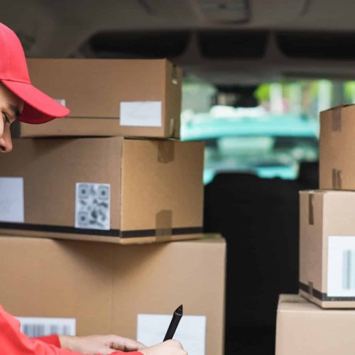 Happy courier with truck signing delivery of cardboard box on tablet - Focus on face