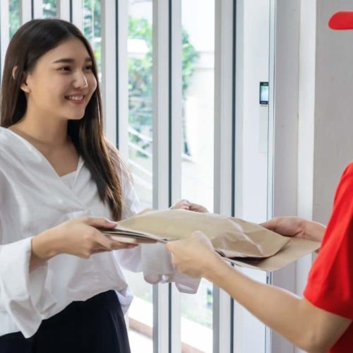 happy-woman-recieving-parcel-from-deliveryman-9GX4ASK-1024x683
